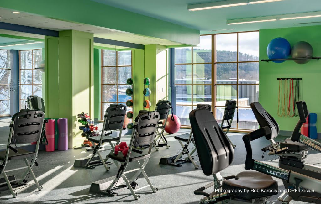 A bright, modern gym with various exercise equipment and weights.