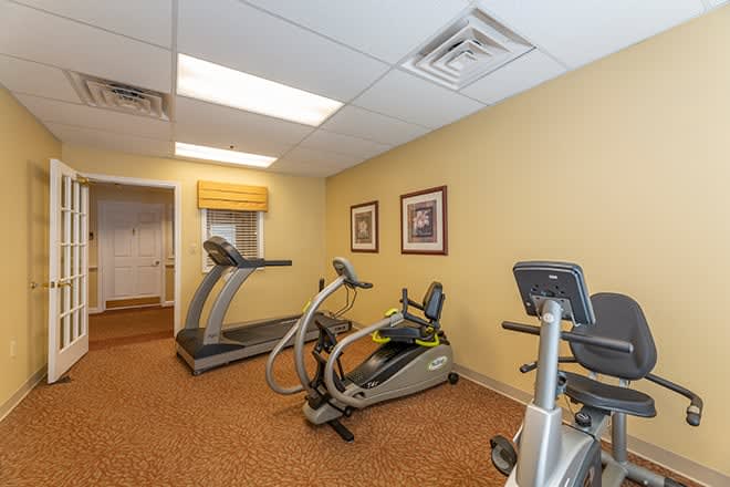 A small gym with exercise equipment including a treadmill and elliptical machine.