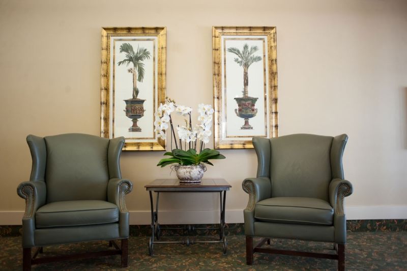 A cozy seating area with two armchairs, framed artwork, and a small table with a potted plant.