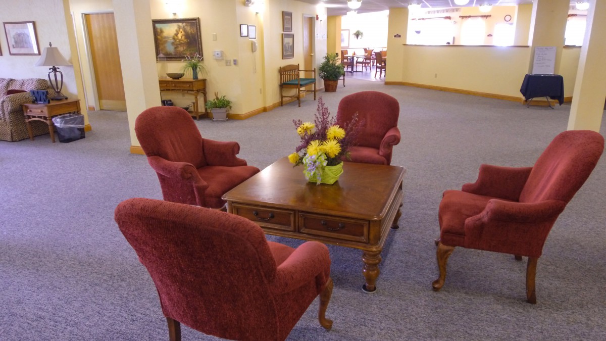 A cozy seating area in a lobby with red chairs and a wooden table decorated with flowers.