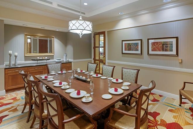 A well-appointed dining room with a large wooden table, set for a meal, surrounded by chairs and decorated with artwork and a chandelier.