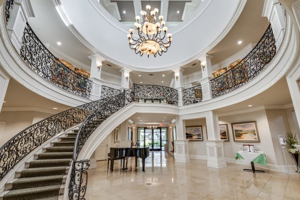 A stunning, opulent mansion interior featuring a grand staircase and elegant chandelier.