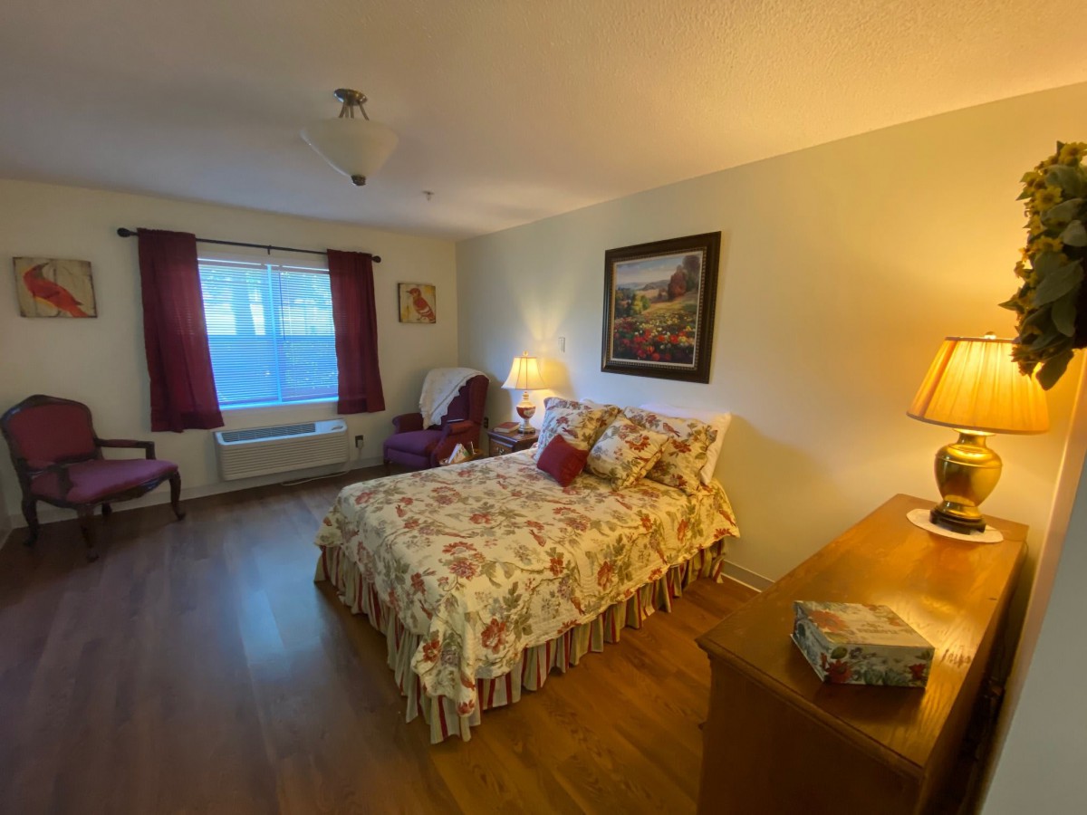A cozy bedroom with floral bedding, an armchair, and warm lighting.