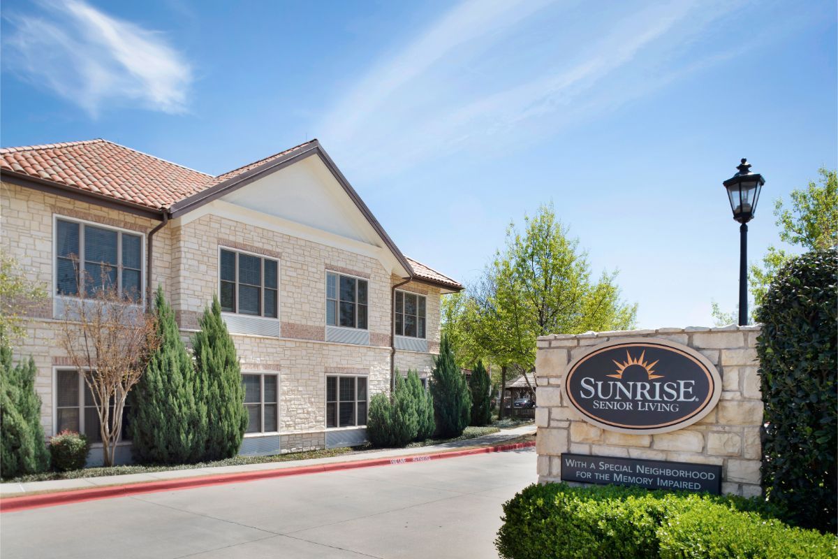 A two-story hotel building with a sign reading 'Sunrise Inn & Suites' set against a blue sky backdrop.