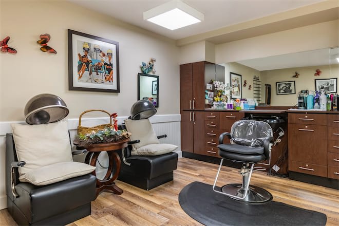 A cozy hair salon interior with chairs, mirrors, and hair drying equipment.