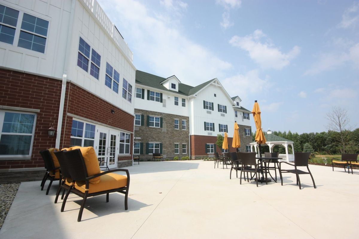 A spacious outdoor patio area with seating and umbrellas in front of a modern building.