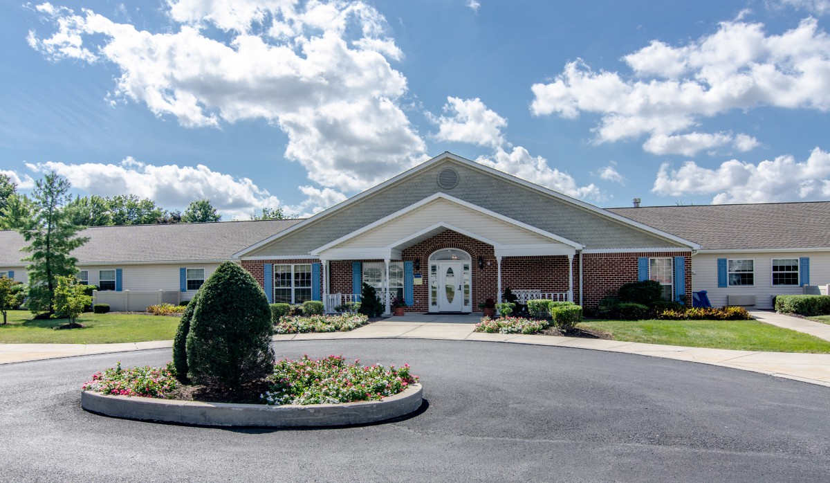 A single-story building with a landscaped entrance under a partly cloudy sky.