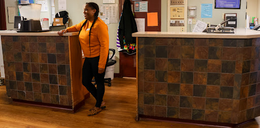 A welcoming interior space with a person in casual attire standing by a reception desk.