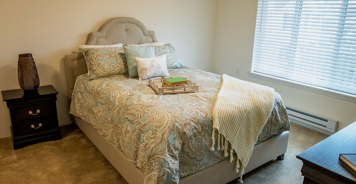 A cozy bedroom with a neatly made bed adorned with decorative pillows and a textured blanket.