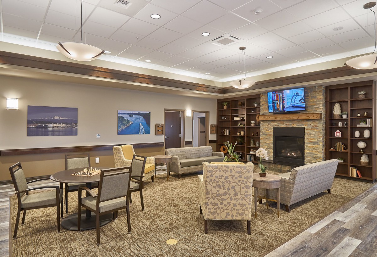 A cozy lounge area with comfortable seating, a fireplace, and a television.