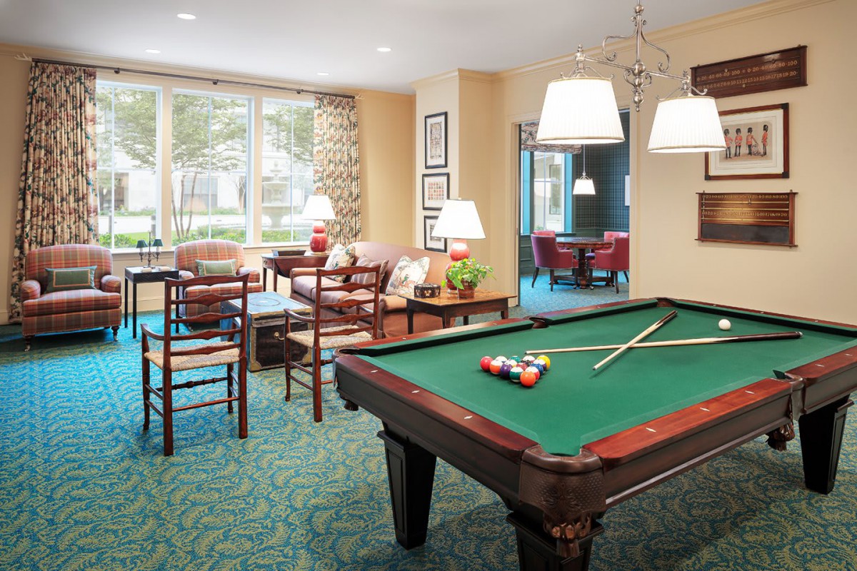 A cozy game room featuring a pool table, comfortable seating, and ambient lighting.