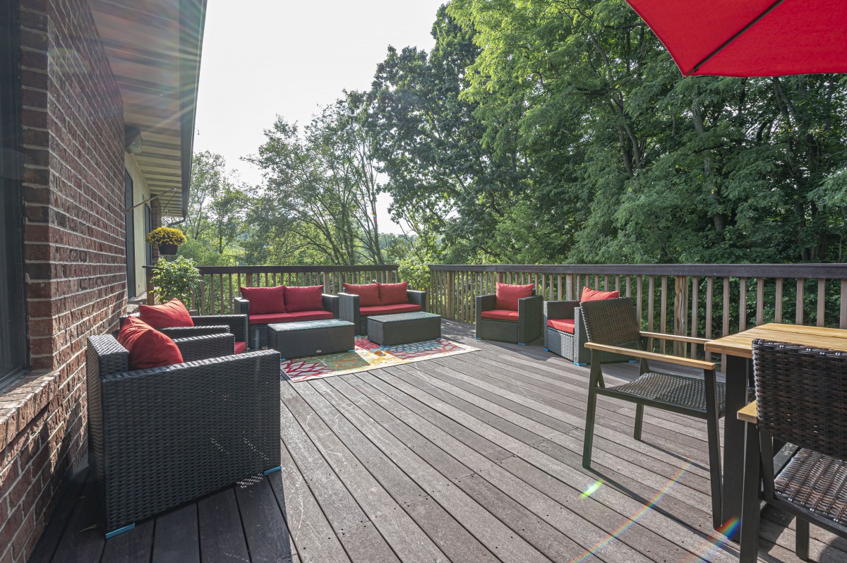 A spacious outdoor deck with comfortable seating and lush greenery.