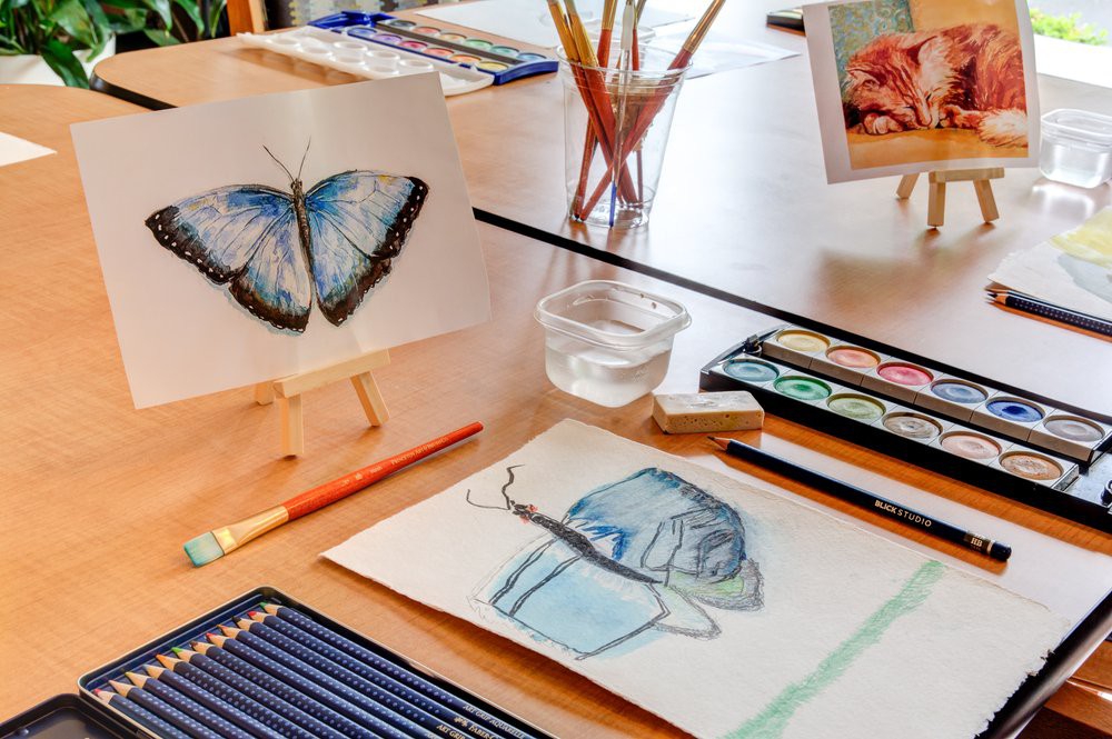 A creative workspace featuring watercolor art supplies and butterfly artwork.