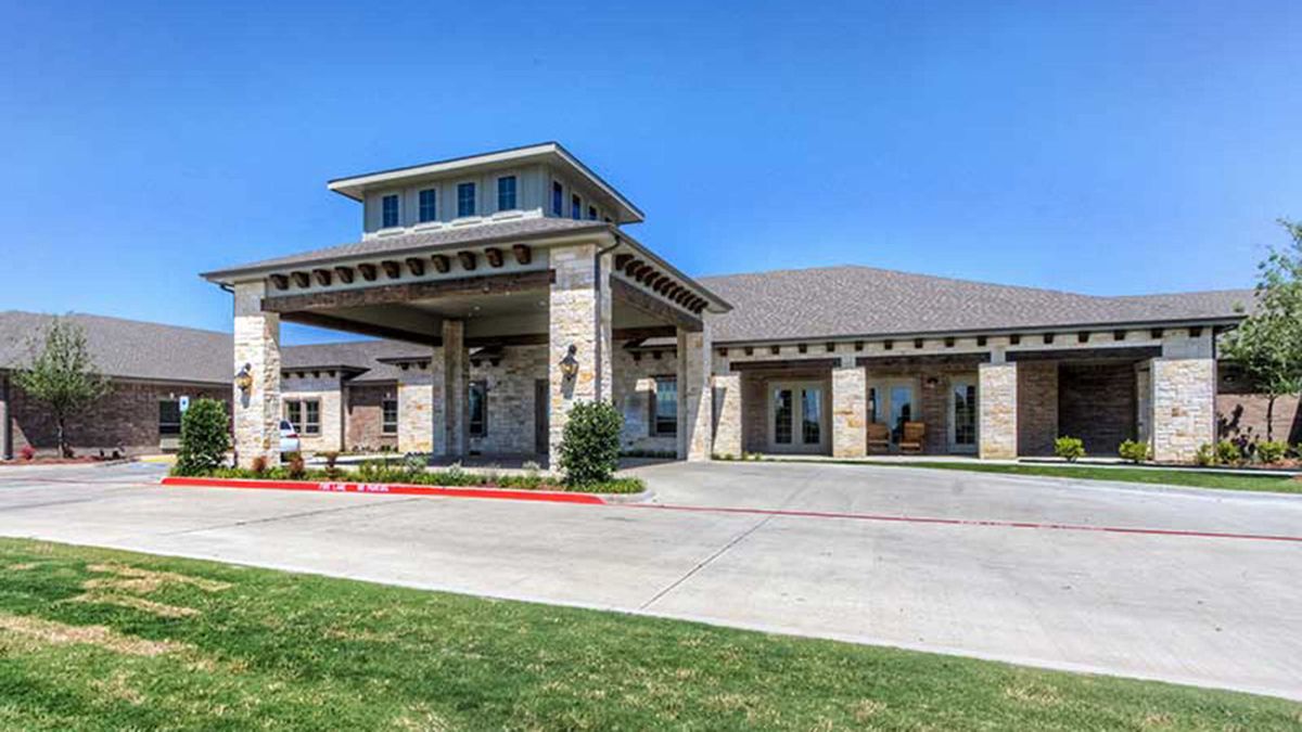 A modern building featuring a large covered entrance and driveway under a clear blue sky.