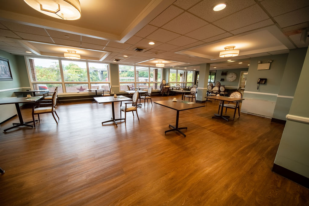 A spacious dining area with wooden flooring and large windows.