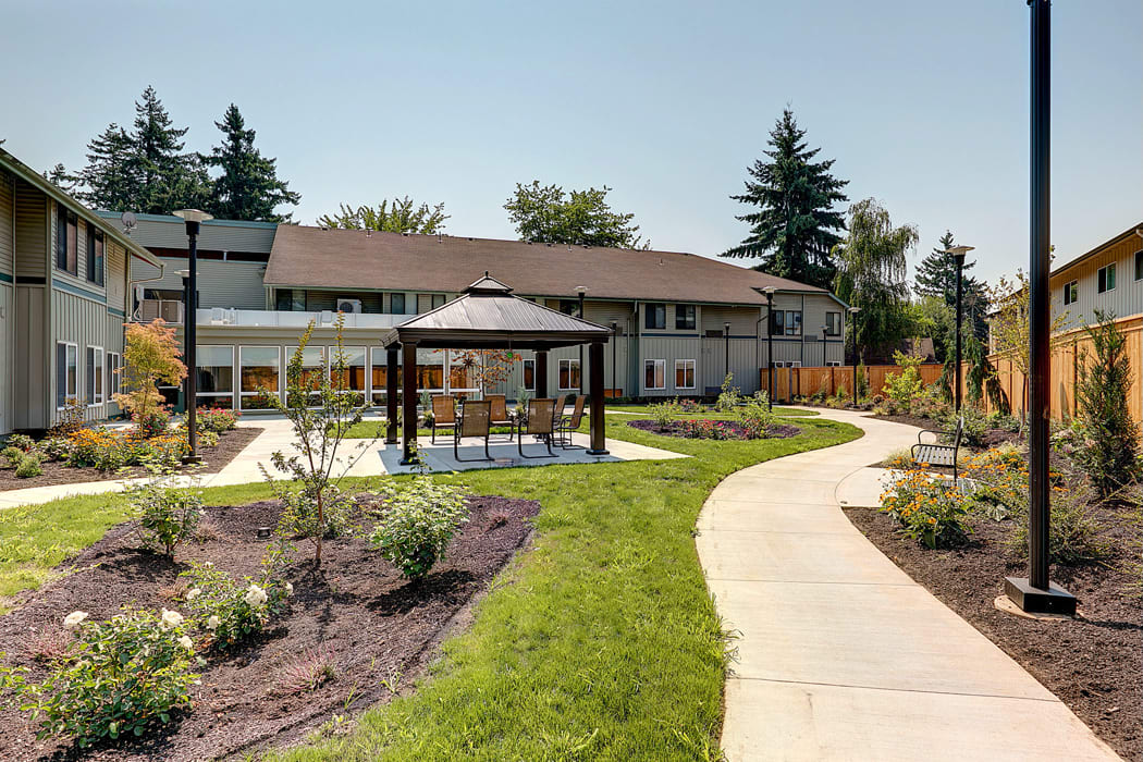 A landscaped garden with a gazebo and pathway leading to a building.