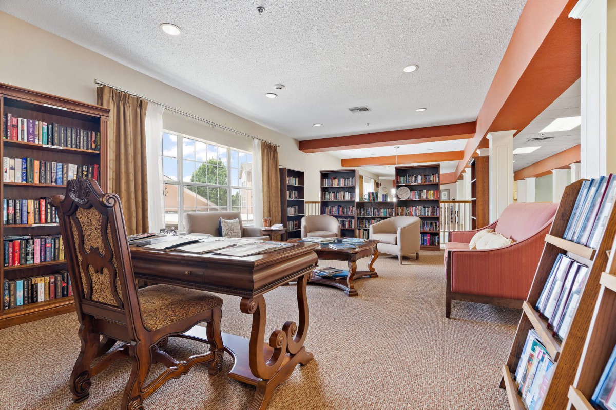 A cozy library room with bookshelves, a desk, and comfortable seating.