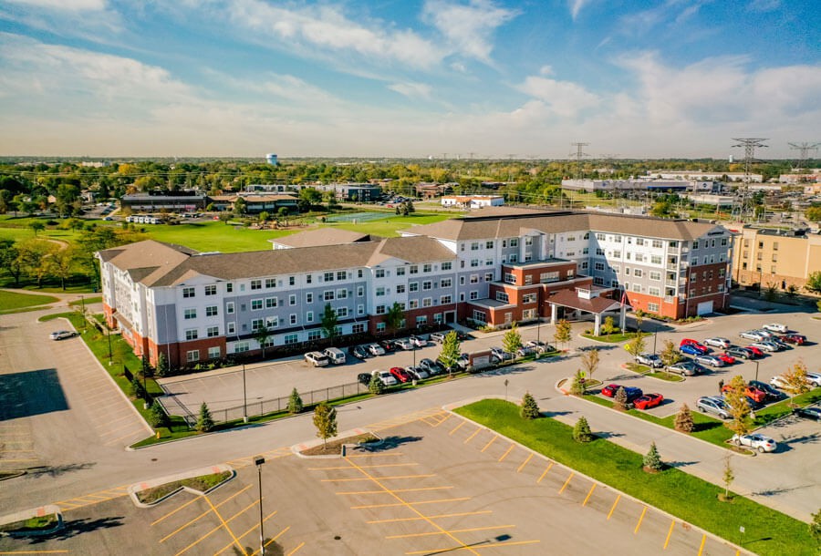Aerial view of a large residential building with a parking lot in a suburban area.