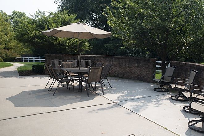 A sunny patio area with outdoor furniture and an umbrella providing shade.