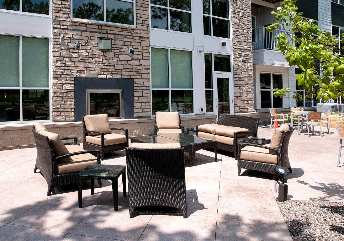 A modern outdoor patio with cushioned seating and a stone wall backdrop.