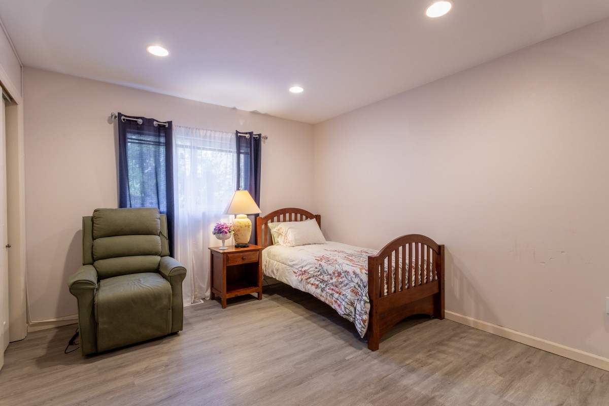 A cozy bedroom with a single bed and recliner chair, featuring minimalist decor.