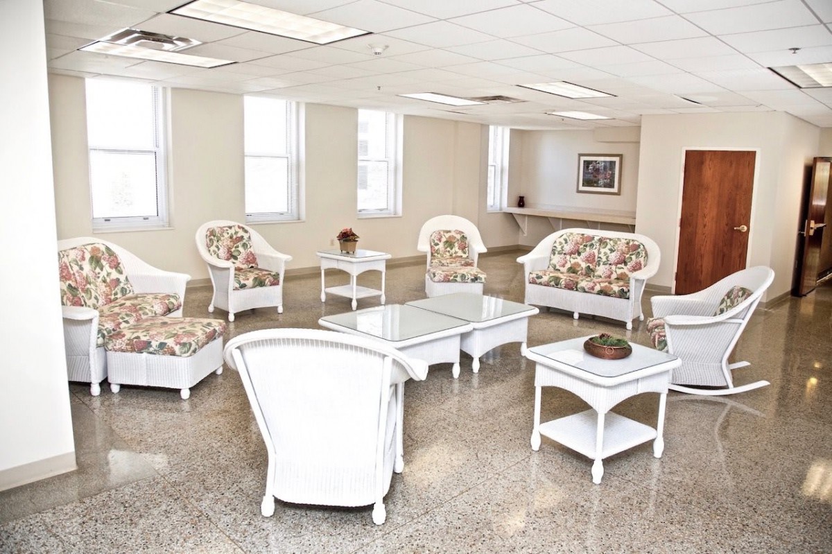 A bright and clean waiting room with white furniture and floral-patterned upholstery.