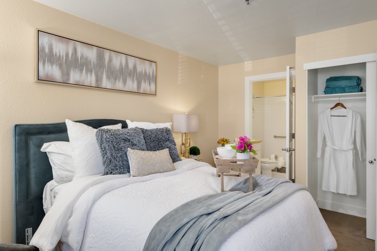 A modern and cozy bedroom with stylish decor and a tray of flowers on the bed.