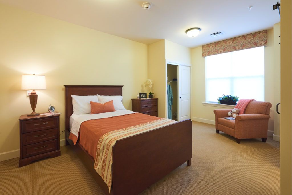 A cozy and well-furnished bedroom with a bed, dresser, and armchair.