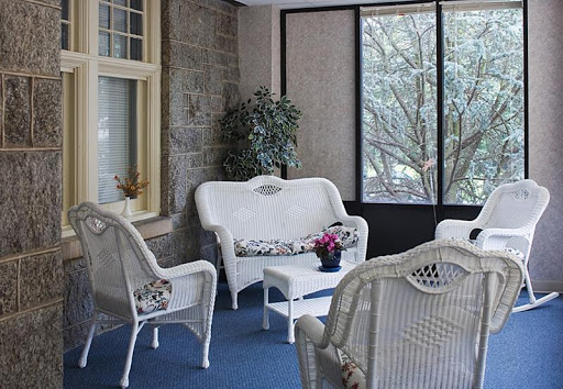 A cozy sitting area with white wicker furniture surrounded by natural light.