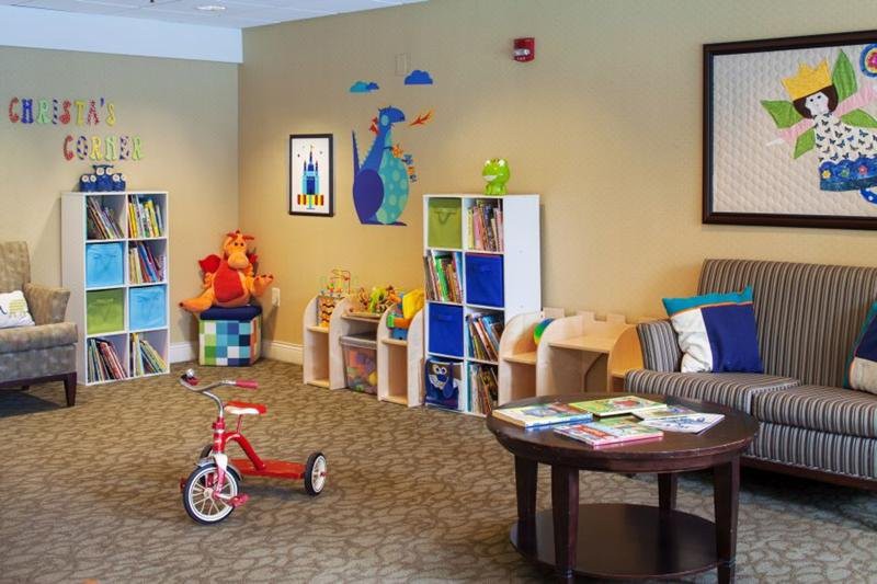 A cozy playroom filled with toys, bookshelves, and a tricycle, providing a fun space for children.