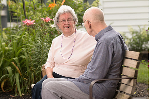 An elderly couple enjoys a warm conversation in a beautiful garden.