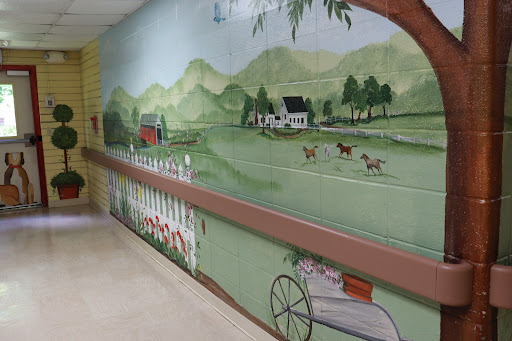 A vibrant mural depicting a serene countryside scene with rolling hills, a farmhouse, and grazing animals.