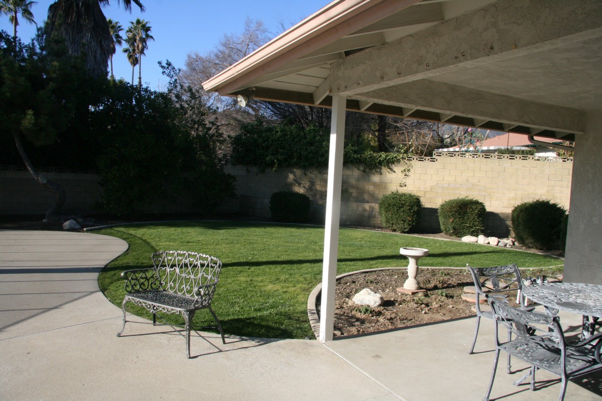 A sunny backyard with a patio, outdoor furniture, and well-maintained landscaping.