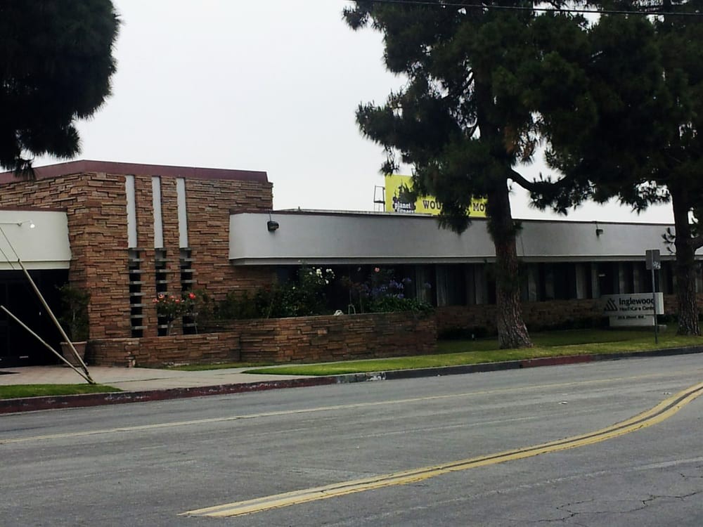 A commercial building on a quiet street with trees and an overcast sky.