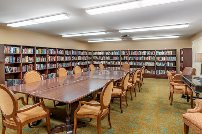 A library meeting room with a long table surrounded by chairs and walls lined with bookshelves.