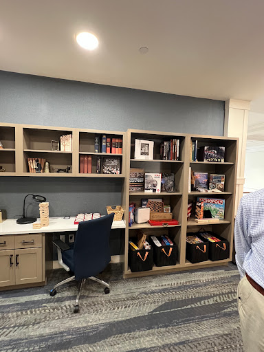 A modern office workspace featuring bookshelves filled with books and decorative items, alongside a neatly arranged desk and chair.