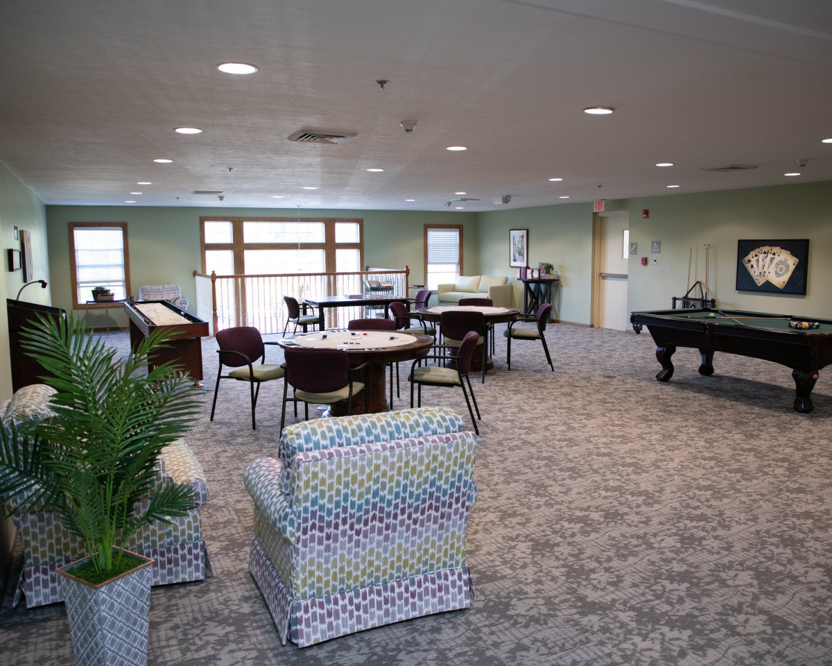 A spacious lounge room featuring comfortable seating, tables, and a pool table for relaxation and recreation.