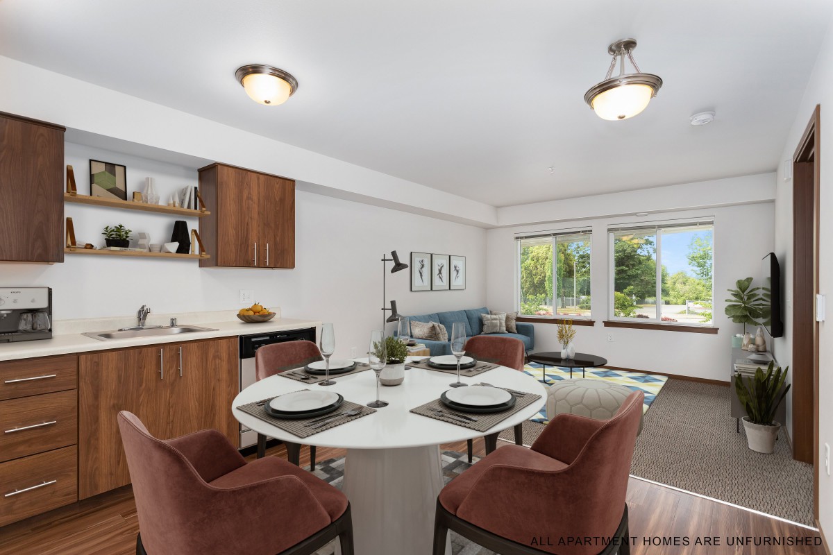 A modern dining room with a round table set for four, featuring large windows and stylish decor.