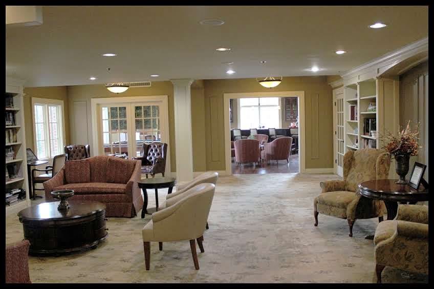 A spacious living room with a traditional decor style, featuring comfortable seating and built-in bookshelves.