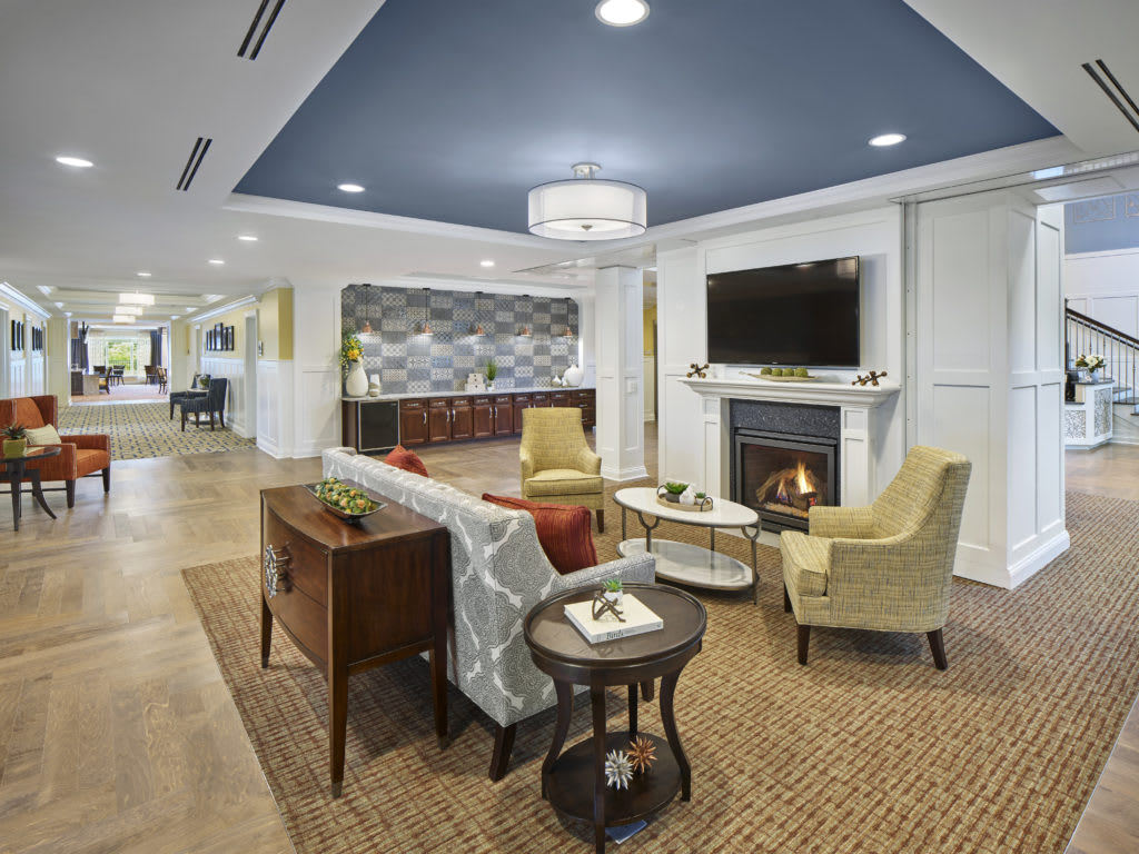 A modern living room with a cozy seating area, featuring a fireplace and television.