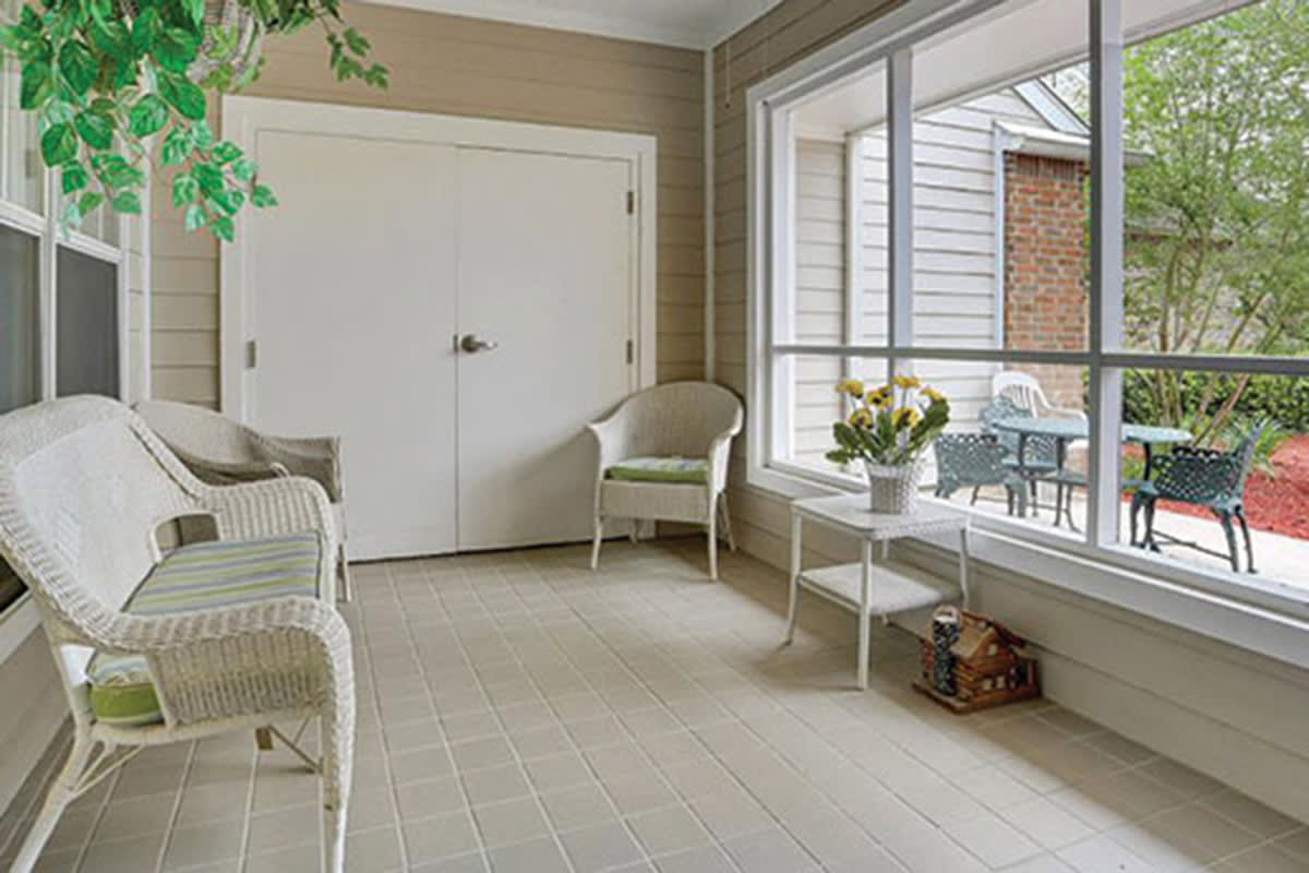 A cozy sunroom with wicker chairs and a large window overlooking a patio.