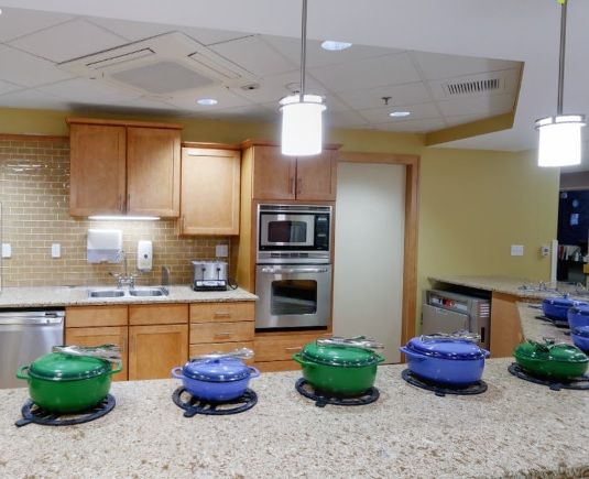 A modern kitchen with a row of colorful cookware on the countertop.