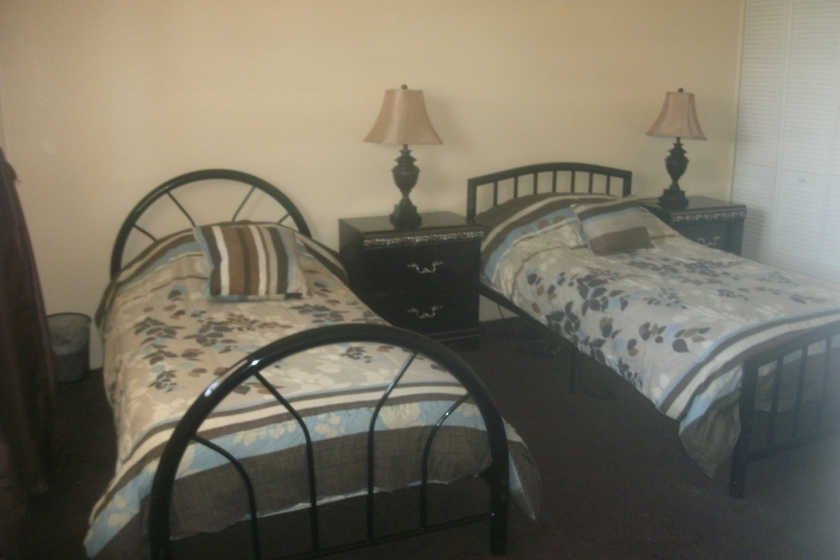 A cozy bedroom featuring twin beds with decorative linens and a shared nightstand with lamps.