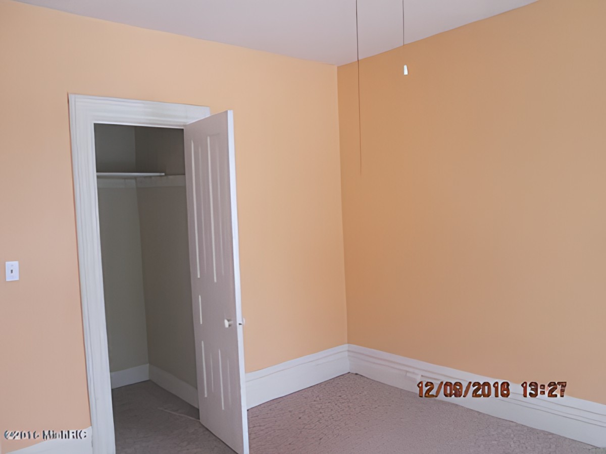 An empty room with peach-colored walls and a closet with an open door.