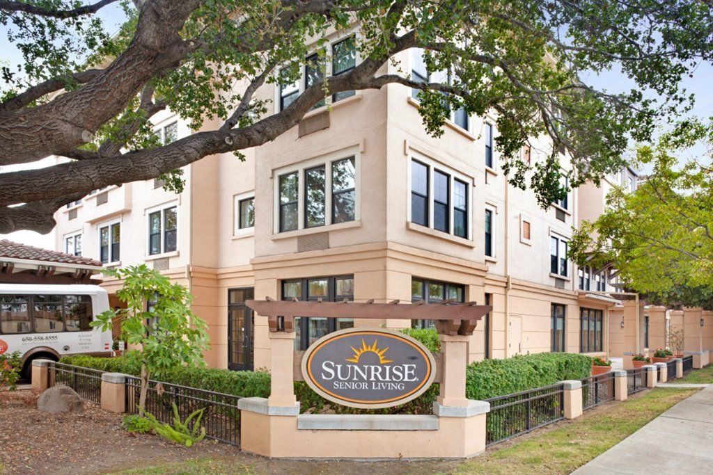 A residential apartment building with a sign in front labeled 'Sunrise'.