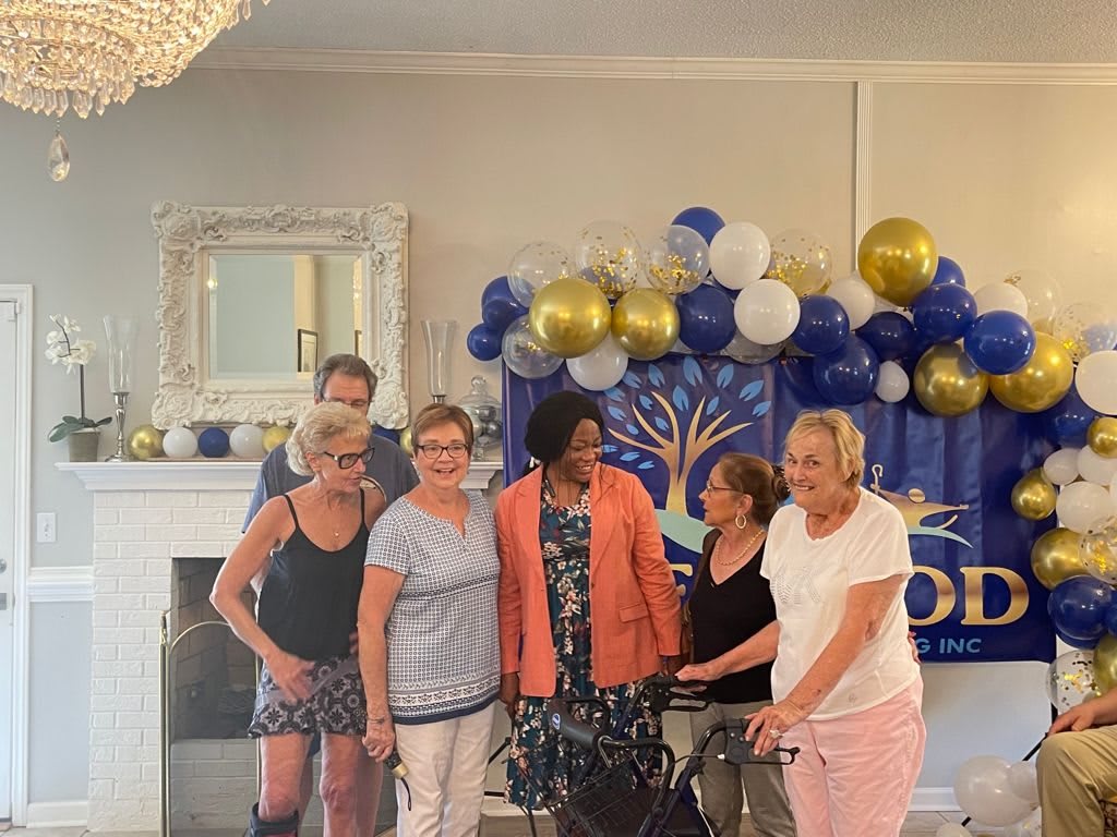 A group of people posing for a celebration with balloons and decorations in the background.