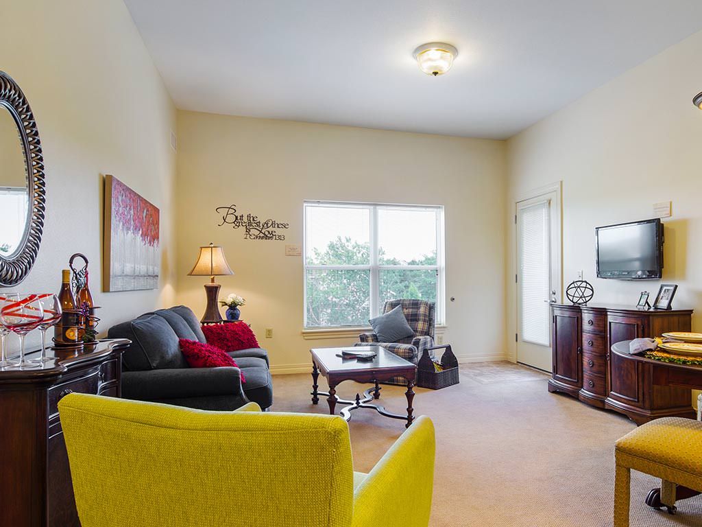 A cozy living room with a sofa, armchair, and coffee table, illuminated by natural light from the window.