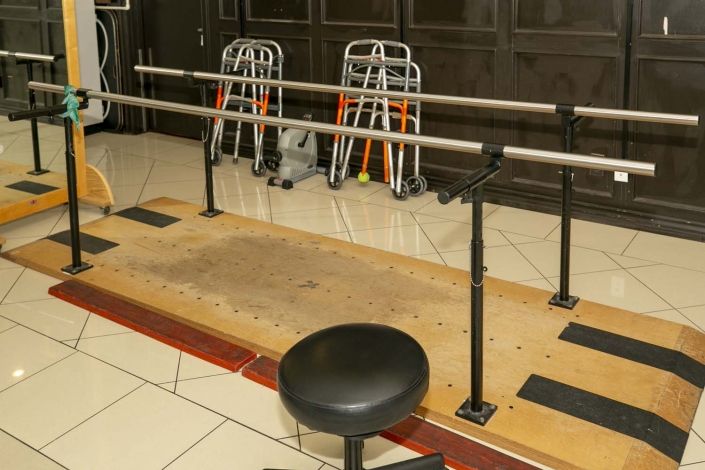 A physical therapy setup featuring parallel bars and walkers in a clinic environment.