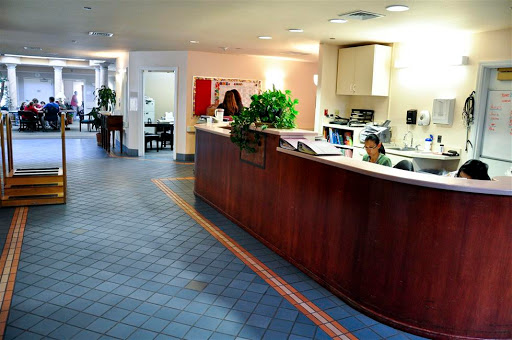 A view of a modern office reception area with a wooden front desk and potted plants.