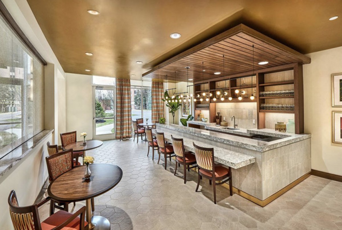 A modern restaurant interior featuring a stylish bar area with counter seating and elegant lighting fixtures.